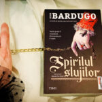 Coperta cărții Spiritul slujitor de Leigh Bardugo, ediția în limba română de la Editura Trei, așezată într-un decor medieval pentru recenzia de Sfântul Valentin