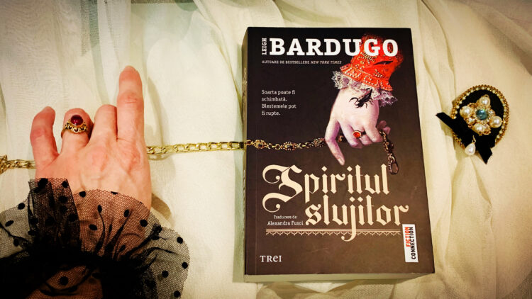 Coperta cărții Spiritul slujitor de Leigh Bardugo, ediția în limba română de la Editura Trei, așezată într-un decor medieval pentru recenzia de Sfântul Valentin