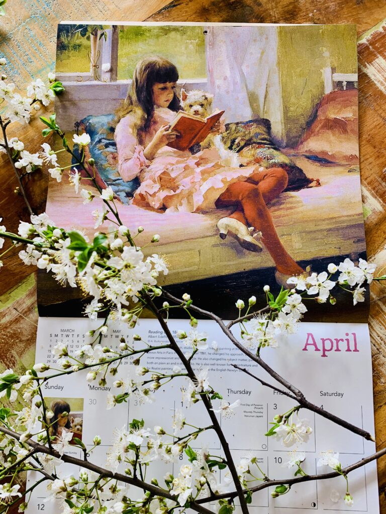 Calendar de perete deschis la luna Aprilie, ilustrând pictura „Buni prieteni (Fetiță citind)” de Albert Edelfelt, încadrat de ramuri înflorite de cireș.