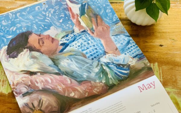Cadru de relaxare cu o ceașcă de cafea, liliac mov și calendarul cu pictura Femeia care citește de Lovis Corinth